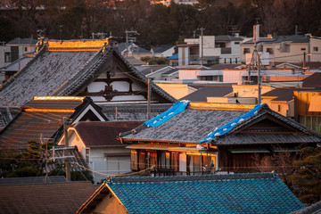 Blue tarp with sandbags on pitched roof of traditional Japanese house damaged by strong typhoon...