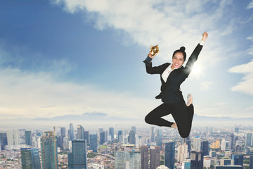 Fototapeta na wymiar Excited businesswoman dancing with a trophy