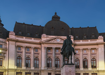 Facade of Central University Library at night. Old building of Bucharest with statue of King Carol...