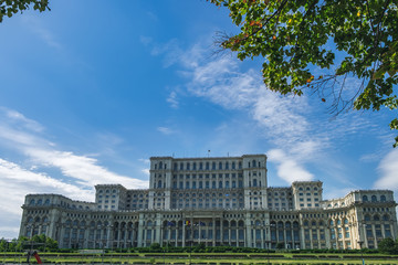 Naklejka premium The Palace of Parliament is seen through the autumn foliage of trees and Liberty Avenue, central part of Bucharest, Romania
