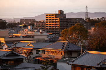Obraz premium Solar panels on roof of traditional Japanese house in city at sunset