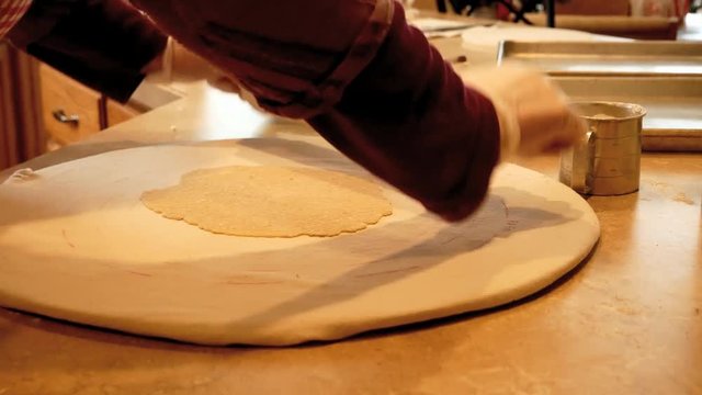 Woman rolling cookie dough with rolling-pin on kitchen counter. Closeup view