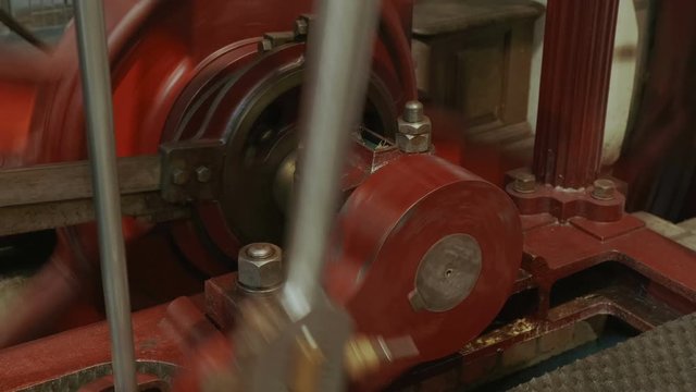 Close-up shot of a flywheel of a single cylinder industrial steam engine in operation
