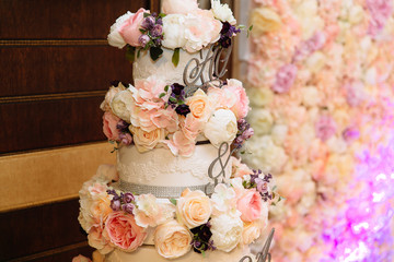 Close-up multilevel wedding cake decorated with flowers stands on a table. Concept of eating, sweets and desserts at a party.