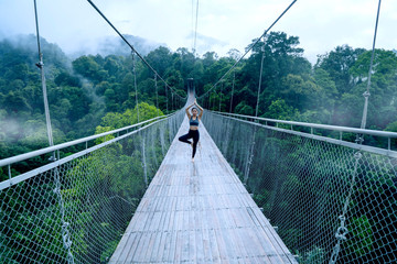 Woman exercising yoga on the suspension bridge