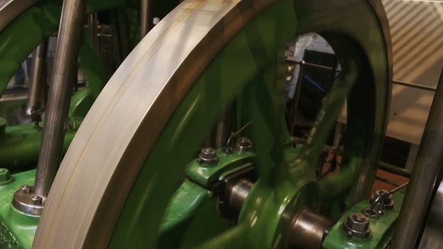 Close-up shot of a flywheel of a single cylinder industrial steam engine in operation