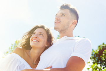 Obraz premium beautiful couple in the white clothes lookig away in future, hug on the background of sky, sun, close-up, summer, love story