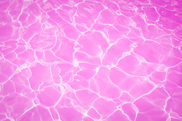 Pink water surface with bright sun light reflections, water in swimming pool background