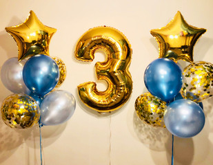 Composition of helium balloons of soft blue, blue, silver and gold, stars and a big number 3