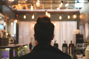 Young business woman waiting for her coffee in a hipster cafe with string lights