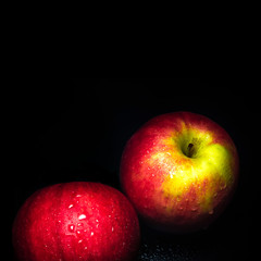 Water droplet on glossy surface of red apple on black background