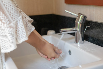 A woman in white dress washing her hands in the sink closeup