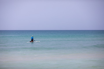 Fototapeta na wymiar Adult man with sup board and paddle on the beach - concept of harmony with the nature, free and healthy living, freelance, remote business. Phuket. Thailand.