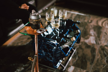 The embers in the bowl of the hookah with interior background. close-up with stylish table