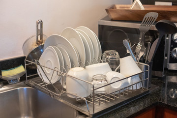 Different clean dishes in dish drying rack on kitchen counter