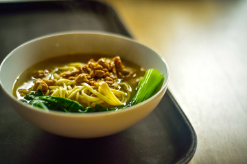 Bowl of chicken vegetable yellow noodle soup on the family dinner table for good fortune and luck celebration