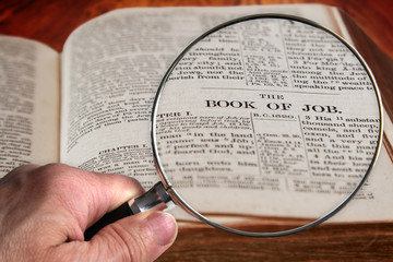 Magnifying Glass on Famous Bible Chapter of Job, a King James Bible which is Public Domain.