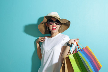 Portrait of beautiful girl holding shopping bags isolated over blue background.