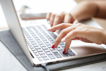 Woman sitting at desk and working at computer close up in hands.