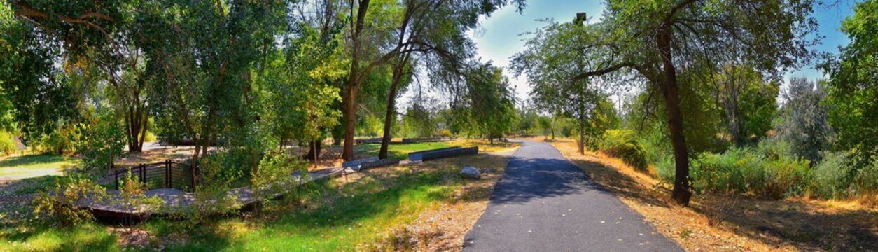 Views of Jordan River Trail with surrounding trees, Russian Olive, cottonwood and silt filled muddy water along the Wasatch Front Rocky Mountains, in Salt Lake City, Utah.