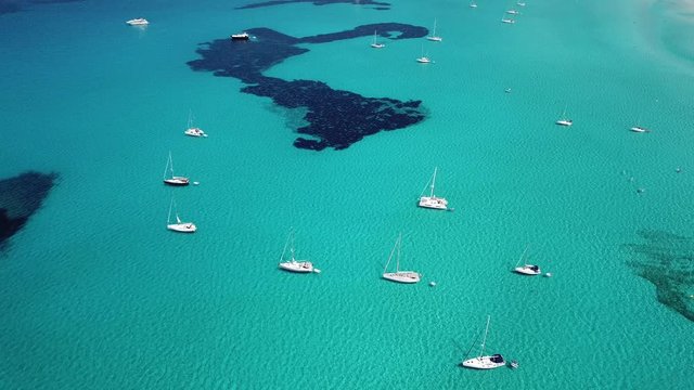 Amazing drone aerial landscape of the charming beach Es Trencs and the boats with a turquoise sea. It has earned the reputation of Caribbean beach of Mallorca. Spain