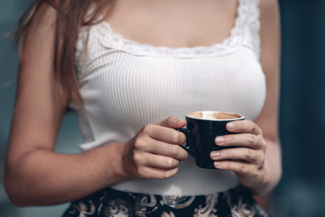 Coffee mug in female hands. Woman drinking hot coffee. Close up photo