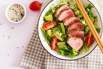 Tuna salad. Japanese traditional salad with pieces of medium-rare grilled Ahi tuna and sesame with fresh vegetable on a bowl. Authentic Japanese food. Top view
