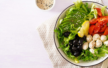 Fresh salad with avocado, tomato, olives and mozzarella  in a  bowl. Buddha bowl. Fitness food. Vegetarian meal. Top view