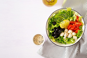 Fresh salad with avocado, tomato, olives and mozzarella  in a  bowl. Buddha bowl. Fitness food. Vegetarian meal. Top view