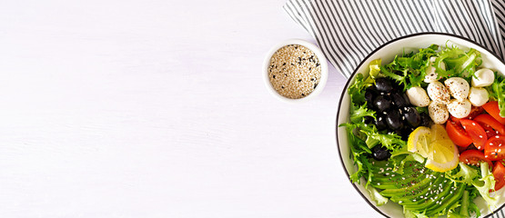 Fresh salad with avocado, tomato, olives and mozzarella  in a  bowl. Buddha bowl. Fitness food. Vegetarian meal. Top view