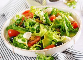 Fresh salad with avocado, tomato, olives and mozzarella  in a  bowl.  Fitness food. Vegetarian meal.
