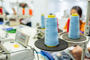 Sewing thread on sewing machine in garment factory workshop