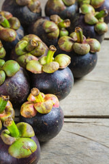 Mangosteen fruit and cross section showing the thick purple skin of the queen of friuts, Delicious mangosteen fruit arranged on wooden background.