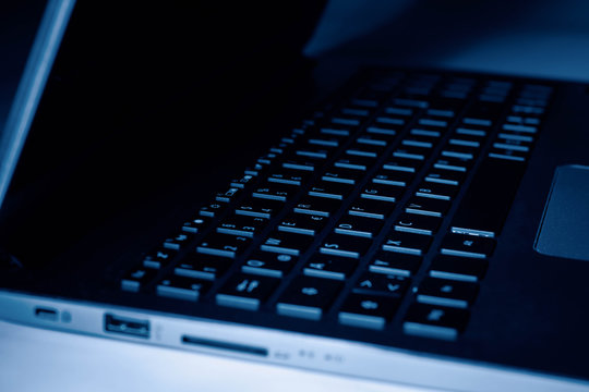 Seitenansicht eines Laptops in bl&auml;ulichem Licht