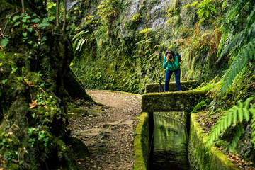 Portrait of young girl in green sweatshirt walking by levana on Madeira island, up in mountains. Hiking by the trail among green, tropical and old forests. Portugal.
