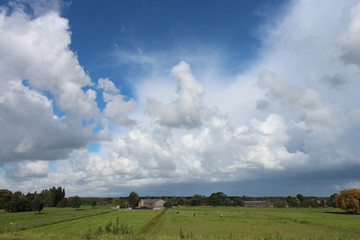 fields and meadows along dyke Hollandsche IJssel river with blue sky and white clouds. The polder behind the dyke is named zuidplaspolder and the lowest area in the Netherlands 