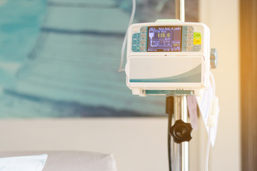 Close up infusion pump of saline solution drip treatment for patient in hospital room at luxury VIP...