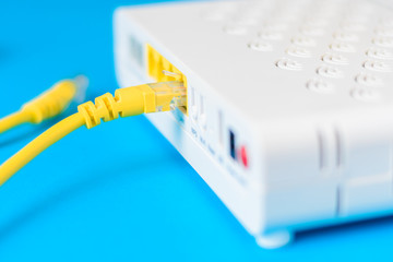 home wireless router with ethernet cable plugged in on blue background, closeup