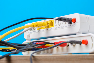home wireless router with ethernet cables plugged in on blue background, closeup