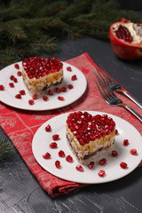 Festive salad in layers in the shape of a heart, decorated with pomegranate seeds on a dark background