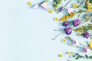 Flowers composition. Yellow and purple flowers on pastel blue background. Spring, easter concept. Flat lay, top view, copy space