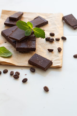 dark chocolate, mint leaves and coffee beans on a white background.