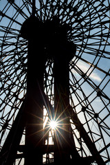 The sun's rays shine through the construction of a carousel. The contours of the ferris wheel in backlight. The sun shines through the ferris wheel.