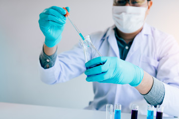 Chemist scientist conducts experiments by synthesising compounds with using dropper in a test tube.