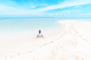 Fototapeta na wymiar Woman sunbathing on scenic white sand beach, rear view, sunny day, turquoise transparent water, real people. Indonesia, Wakatobi islands