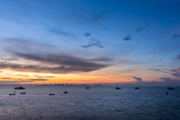 Fototapeta premium Fishing boat floats in sea with sunrise shining and with cloud. View from Koh Larn, Chon Buri THAILAND.