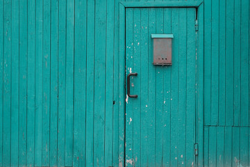 Fototapeta na wymiar Mailbox on wooden door sea green color. Along the wooden fence with copy space on the left side