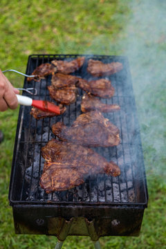 Man basting meat with barbecue sauce while grilling / barbeque