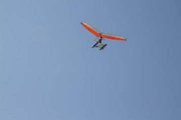 Fototapeta na wymiar The motorized hang flies by the blue sky. UL-Trike flying in the light of the setting sun