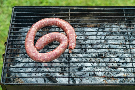 Grilling sausage on barbecue grill, BBQ in the garden